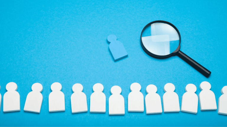 A row of white paper people with a blue person being selected. Running a recruitment agency is about picking the best candidates for our client's roles