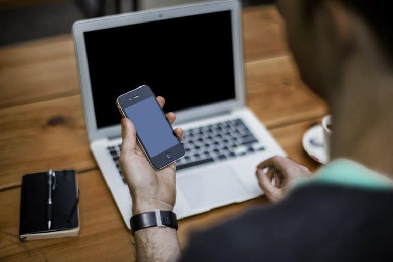 A candidate actively searching for jobs on his phone and laptop