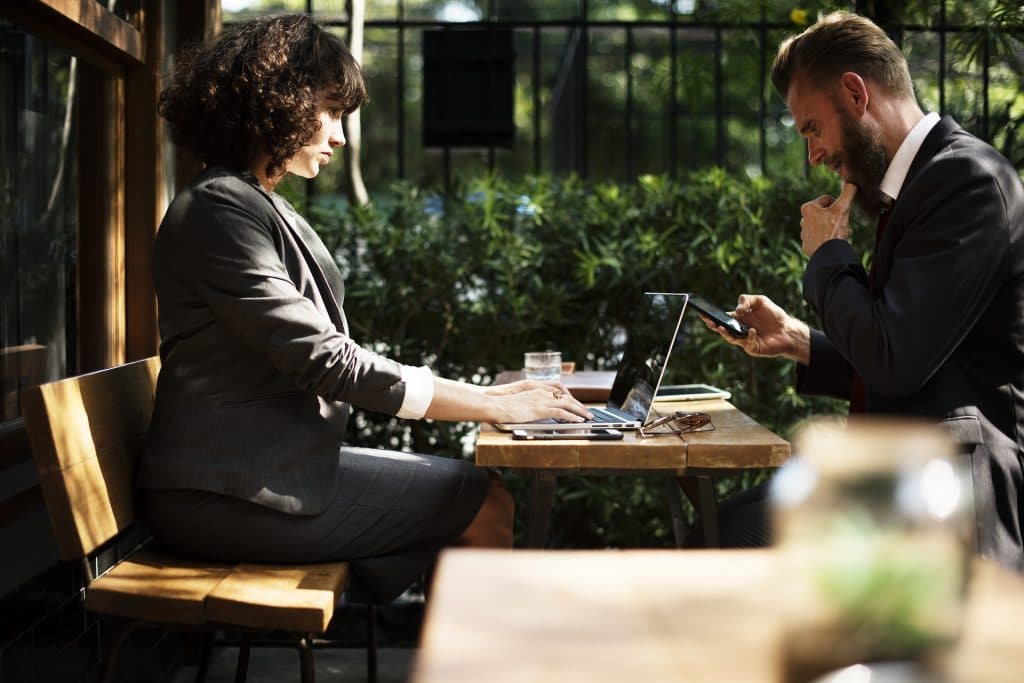 A business man and woman working at a laptop, outside on a sunny day