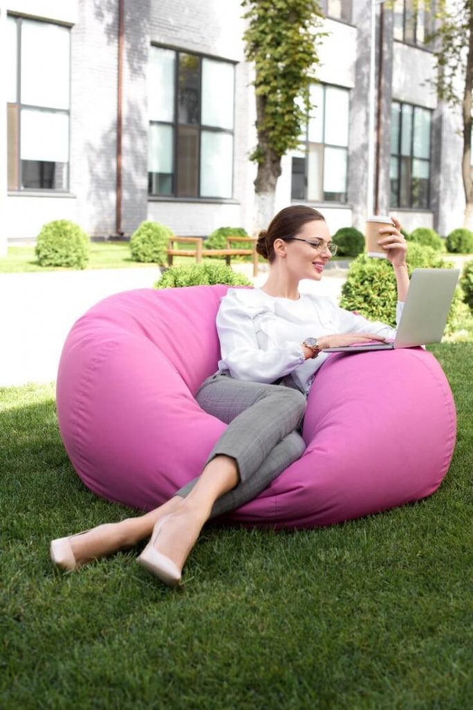 Lady proving why summer is the perfect time to apply for a new job by submitting applications from her pink bean bag in the garden