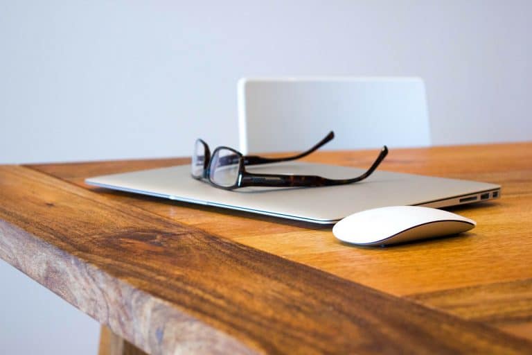 A pair of glasses lying upside down on a closed laptop on a desk left empty due to tech skills shortages