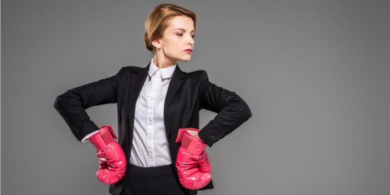 a woman looks confident in a suit, wearing boxing gloves and ready for a fight