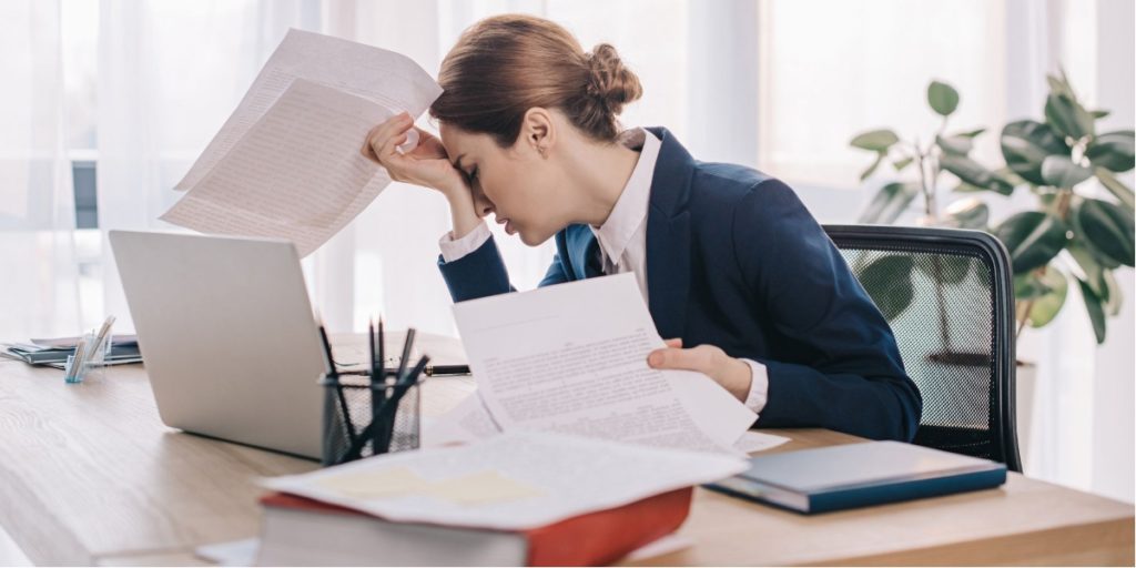 A smart woman working in a corporate job seems stress and tired of all the paperwork and burocrazy