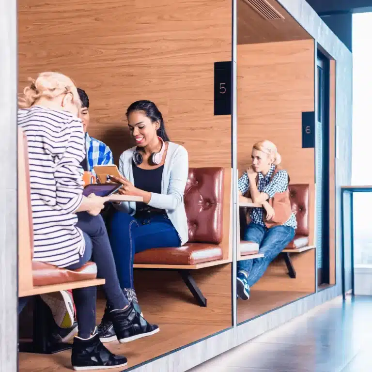 A group of young tech students sit together on their break, chatting about technology while checking on their LinkedIn on their iPads