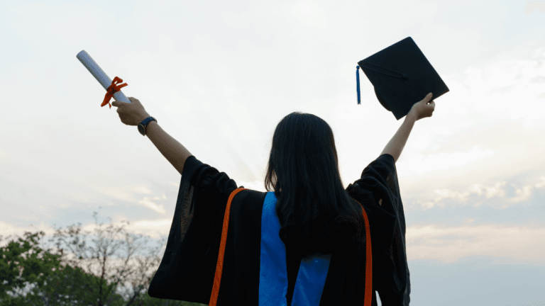 University graduate holds her qualification and graduation cap to the sky