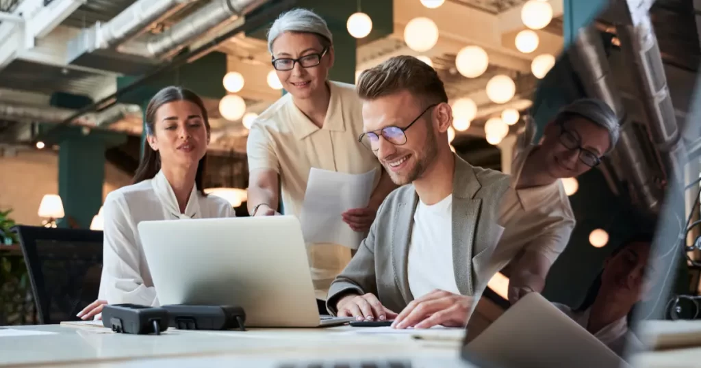 Two women work discuss a project with a male IT contractor their employer has hired to help them in summer