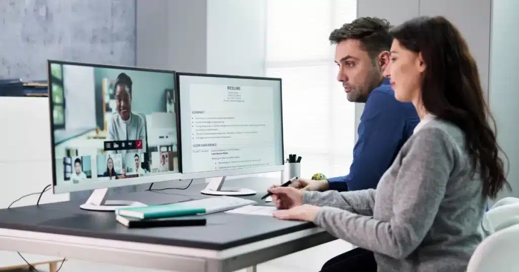 A hiring manager and a talent manager speak to a female candidate through a video interview software