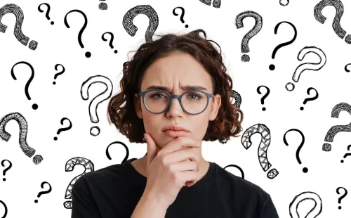 A young woman in glasses looks puzzled after her mind went blank in a job interview and she lost track of her words