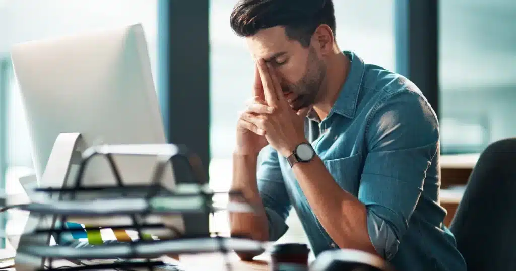 A man takes a deep breath, feeling stressed and frustrated about his company's recruitment process