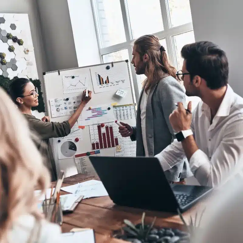 A woman discusses data forecasts with her team, using data visualisation examples