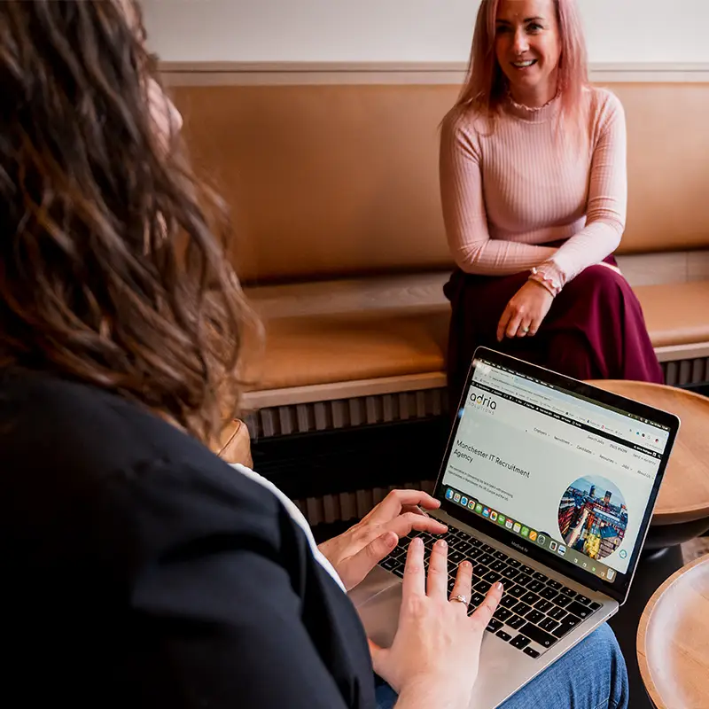 Marta sits with her laptop on her lap, in the middle of a chat with Emma about recruitment marketing strategies