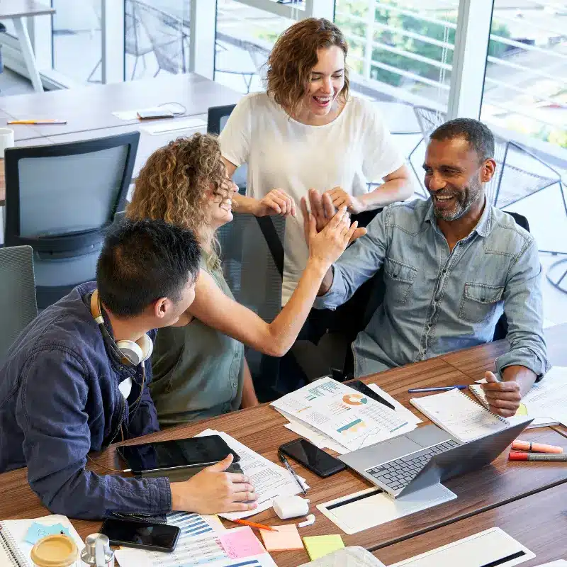 A team of two white women, an asian men and a black men celebrate the success of their digital marketing campaign