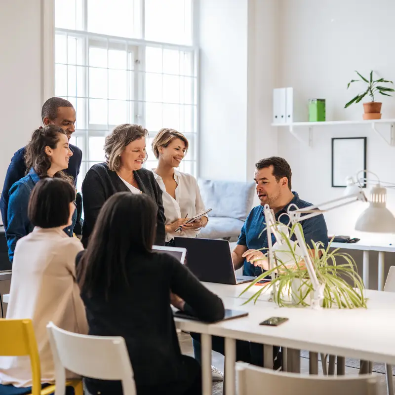 A team of five women and one men of different ages learn in the office about using AI tools at work