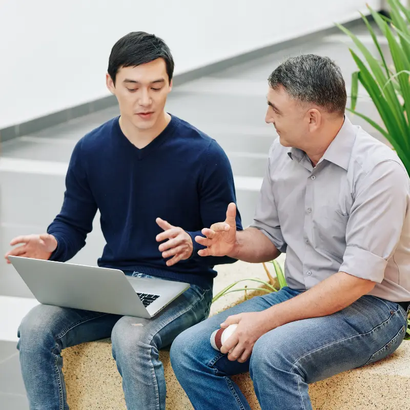 a mid-level programmer and a senior software engineer have an informal chat in the office hall to discuss a project